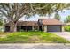 A beautiful single-story home with a stone facade and two-car garage sits under a large shade tree at 4612 Masefield Pl, Sarasota, FL 34241