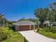 Charming single-story home featuring a two-car garage and beautifully landscaped front yard under a clear blue sky at 4758 Breezy Pines Blvd, Sarasota, FL 34232