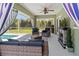 Screened-in lanai with comfortable seating, a ceiling fan, and an outdoor fireplace overlooking the pool at 4758 Breezy Pines Blvd, Sarasota, FL 34232