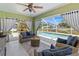 Covered patio features wicker furniture, a fireplace, and views of the pool with blue curtains at 4758 Breezy Pines Blvd, Sarasota, FL 34232