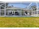 Backyard pool has a screen enclosure, a patio seating area, and lush green grass at 4758 Breezy Pines Blvd, Sarasota, FL 34232