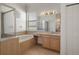 Well-lit bathroom features a window, tiled tub, and separate glass shower at 4951 Brightstone Pl, Spring Hill, FL 34609