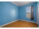Cozy bedroom boasts blue walls, wood floors, and a bright window at 4951 Brightstone Pl, Spring Hill, FL 34609