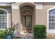 Inviting front entryway with a glass-paneled door, decorative light fixture, and manicured shrubbery at 4951 Brightstone Pl, Spring Hill, FL 34609