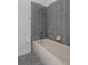 Combined tub/shower includes gray tiling, silver fixtures, and a white tub at 4951 Brightstone Pl, Spring Hill, FL 34609