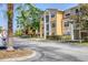 Inviting yellow condo building showcasing manicured landscaping and ample parking space at 5552 Bentgrass Dr # 7-301, Sarasota, FL 34235