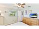 Well-lit bedroom with ceiling fan, light walls, door to another room, and large wooden dresser at 5603 1St Avenue Dr Nw, Bradenton, FL 34209