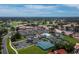 An aerial view shows the community's tennis courts, clubhouse, parking and overall layout amid lush surroundings at 6110 Country Club Way # 102, Sarasota, FL 34243