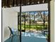 Relaxing screened lanai with a chair and a view of the lush green lawn and mature trees at 6110 Country Club Way # 102, Sarasota, FL 34243