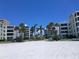 Serene beach with white sand leading up to beachfront condos and palm trees at 6150 Midnight Pass Rd # V4, Sarasota, FL 34242