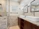Bathroom featuring double sinks, vanity, and walk-in shower with stone tile at 6300 Midnight Pass Rd # 5, Sarasota, FL 34242