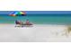 Tranquil beach scene with lounge chairs, colorful umbrella, and clear turquoise water, perfect for relaxation at 6300 Midnight Pass Rd # 5, Sarasota, FL 34242