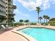 Pool with steps to beach views, lounge chairs and palm trees under sunny skies at 6300 Midnight Pass Rd # 5, Sarasota, FL 34242