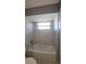 A well-lit bathroom with a window, a new tub and shower with white and gray tile surround at 6360 Jordan St, North Port, FL 34287