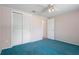 Cozy bedroom features plush blue carpet, a ceiling fan, and a closet with folding doors at 8413 Lincolnshire Dr, Hudson, FL 34667