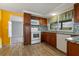 Galley kitchen features wood cabinets, white appliances, mosaic backsplash, and wood-look tile flooring at 8413 Lincolnshire Dr, Hudson, FL 34667
