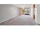 View of the living room with carpet flooring and sliding glass door access to the lanai at 8413 Lincolnshire Dr, Hudson, FL 34667