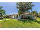 Street view of the home featuring an attached garage, mature trees, and well-maintained landscaping at 8730 Filson Pl, Sarasota, FL 34231