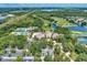 Aerial view featuring the clubhouse, tennis courts, and parking area, all surrounded by beautiful trees at 8731 52Nd E Dr, Bradenton, FL 34211