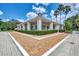 Corner view of the pool house with pillars, green hedges, and gravel landscaping at 8731 52Nd E Dr, Bradenton, FL 34211