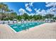 Resort-style pool area featuring a large pool, sun loungers, and umbrellas amidst lush landscaping at 8731 52Nd E Dr, Bradenton, FL 34211