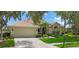 Well-maintained home with lush lawn, mature trees and bushes, and a paved driveway leading to an attached garage at 9635 Discovery Ter, Bradenton, FL 34212