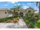Charming home featuring a tiled roof, black front door, and lush landscaping with palm trees and colorful flowers at 9635 Discovery Ter, Bradenton, FL 34212