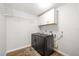 Laundry room with grey washer and dryer, white cabinets, and laminate wood floors at 1040 Hope St, Venice, FL 34285