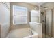 Bright bathroom with a tub, glass-enclosed shower, and neutral tile at 11411 Spring Gate Trl, Bradenton, FL 34211