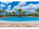 Large community pool surrounded by tropical palms and lounge chairs at 11411 Spring Gate Trl, Bradenton, FL 34211