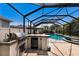 Enclosed pool area featuring a grill, sink, and countertop for entertaining guests at 11411 Spring Gate Trl, Bradenton, FL 34211