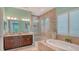 Luxurious bathroom with a soaking tub, glass-enclosed shower, dual vanity sinks, and tiled flooring at 11603 Bluebird Pl, Lakewood Ranch, FL 34211