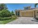 Charming home featuring a tile roof, two-car garage, brick paver driveway and lush green landscaping at 11603 Bluebird Pl, Lakewood Ranch, FL 34211