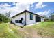 An exterior view shows this home's back lawn, landscaping, AC unit and screened porch at 11960 De Leon Dr, North Port, FL 34287