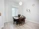 Bright dining area features modern lighting fixture, wood-look floors and white sheer curtains at 11960 De Leon Dr, North Port, FL 34287