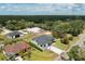 Aerial view of a well-maintained home with a paved driveway, lush landscaping, and nearby woods at 11960 De Leon Dr, North Port, FL 34287