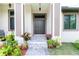 A close up of the home's front entrance, featuring a tasteful walkway and front yard landscaping and flower pots at 11960 De Leon Dr, North Port, FL 34287