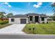 Attractive single-story home with a paved driveway, a manicured lawn, and decorative landscaping at 11960 De Leon Dr, North Port, FL 34287
