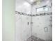 A spacious walk-in shower with white marble tiles and mosaic accents and glass door at 11960 De Leon Dr, North Port, FL 34287