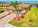 Beautiful home features a terracotta roof, two-car garage, paver driveway, tropical landscaping, and a lush green lawn at 12230 Amica Loop, Venice, FL 34293