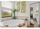 Bright bathroom features a soaking tub with tile surround, leafy art prints, and a decorative full length mirror at 12230 Amica Loop, Venice, FL 34293