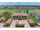 Aerial view of a condo building with multiple units, golf course, lake and parking under a sunny sky at 13711 Messina Loop # 102, Lakewood Ranch, FL 34211