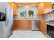 Well-lit kitchen with stainless steel appliances, light wood cabinets, and a window overlooking lush greenery at 1475 Bayshore Dr, Englewood, FL 34223