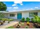 Charming front entrance with a bright blue door, manicured landscaping, and a freshly painted white brick facade at 1915 38Th W St, Bradenton, FL 34205
