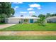 Charming one story home featuring an updated metal roof, manicured landscaping, and a turquoise front door at 1915 38Th W St, Bradenton, FL 34205
