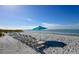 A row of beach chairs and an umbrella offer a relaxing setting on a beautiful beach with clear blue water at 2045 Gulf Of Mexico Dr # M1-515, Longboat Key, FL 34228