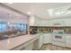 Well-lit kitchen featuring white cabinetry, and a tile backsplash with views into the dining and living rooms at 2045 Gulf Of Mexico Dr # M1-515, Longboat Key, FL 34228