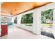 Bright sunroom with wood ceiling connects to the backyard patio and offers a view of lush greenery at 302 Pavonia Rd, Nokomis, FL 34275