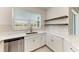 Bright kitchen featuring white cabinetry, stainless steel dishwasher, quartz countertops, and open wood shelving at 305 Via Tuscany Ave, Sarasota, FL 34243
