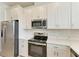 Modern kitchen featuring stainless steel appliances, white cabinets, stylish backsplash, and quartz countertops at 305 Via Tuscany Ave, Sarasota, FL 34243